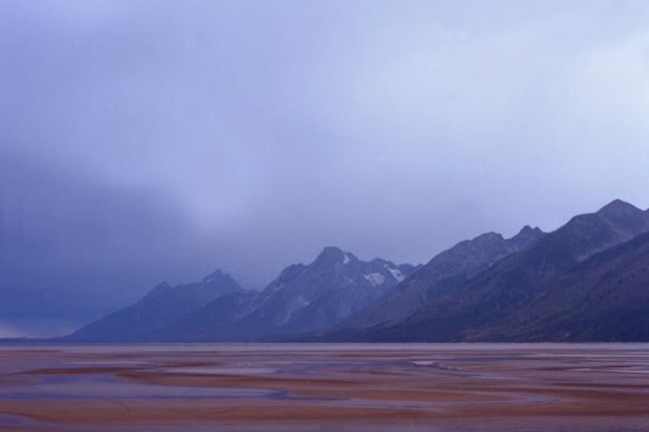 brown, wet plain leads to tetons on an overcast day