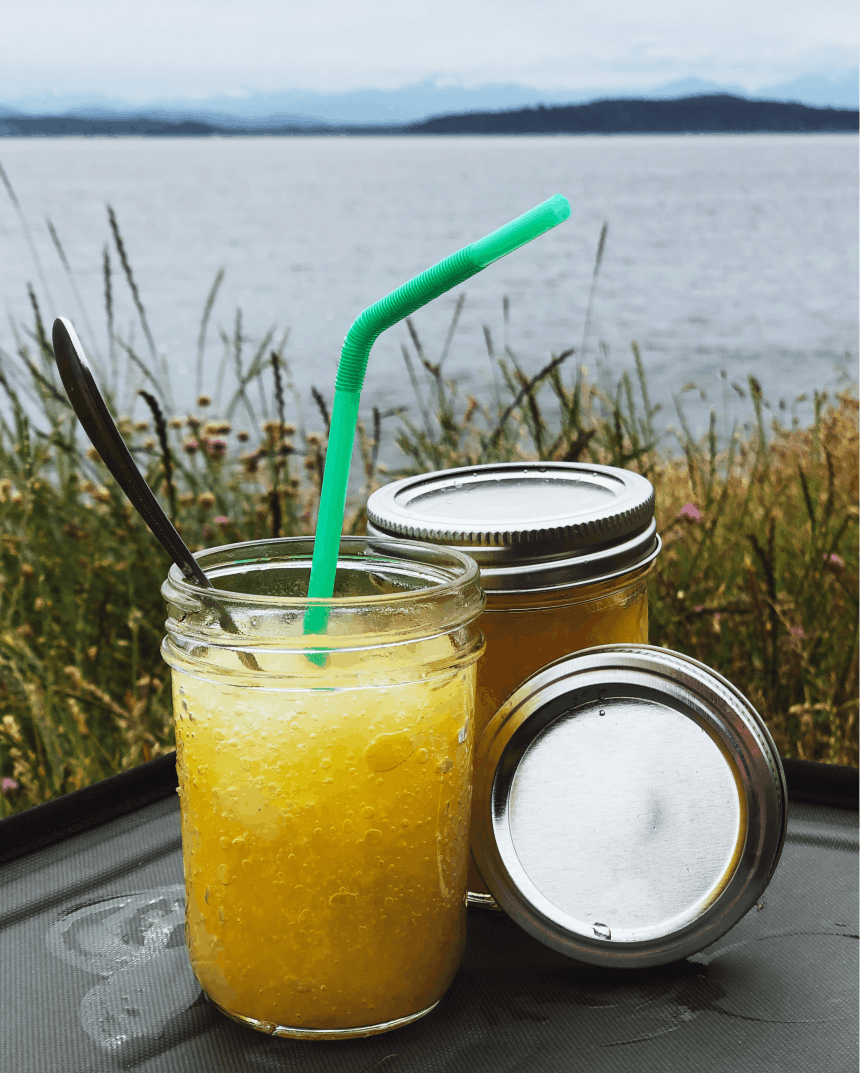 bourbon slush cocktail set on a black table with a lake in the background