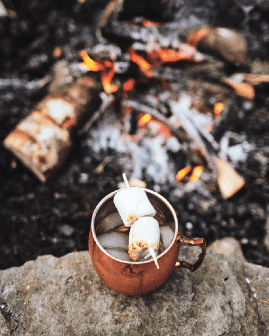 melted marshmallows stuck through with a wood skewer balanced over the lip of a copper mug