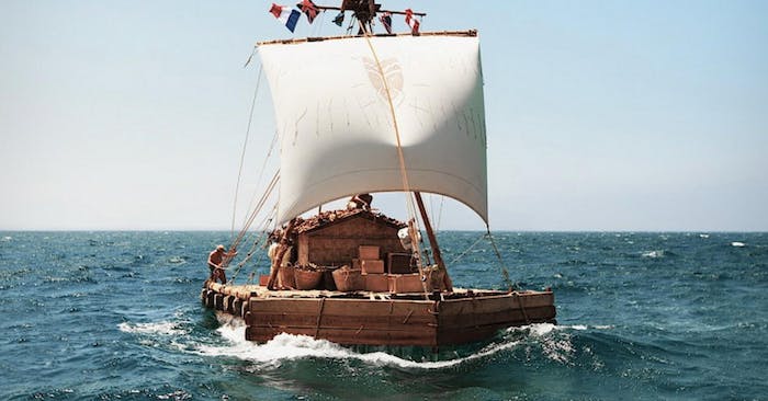 wooden raft at sea with single sail being steered by a man