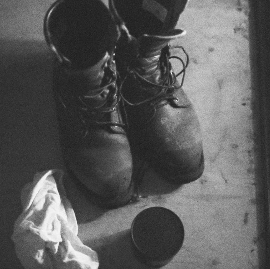 black and white image of workboots with a cloth and polish