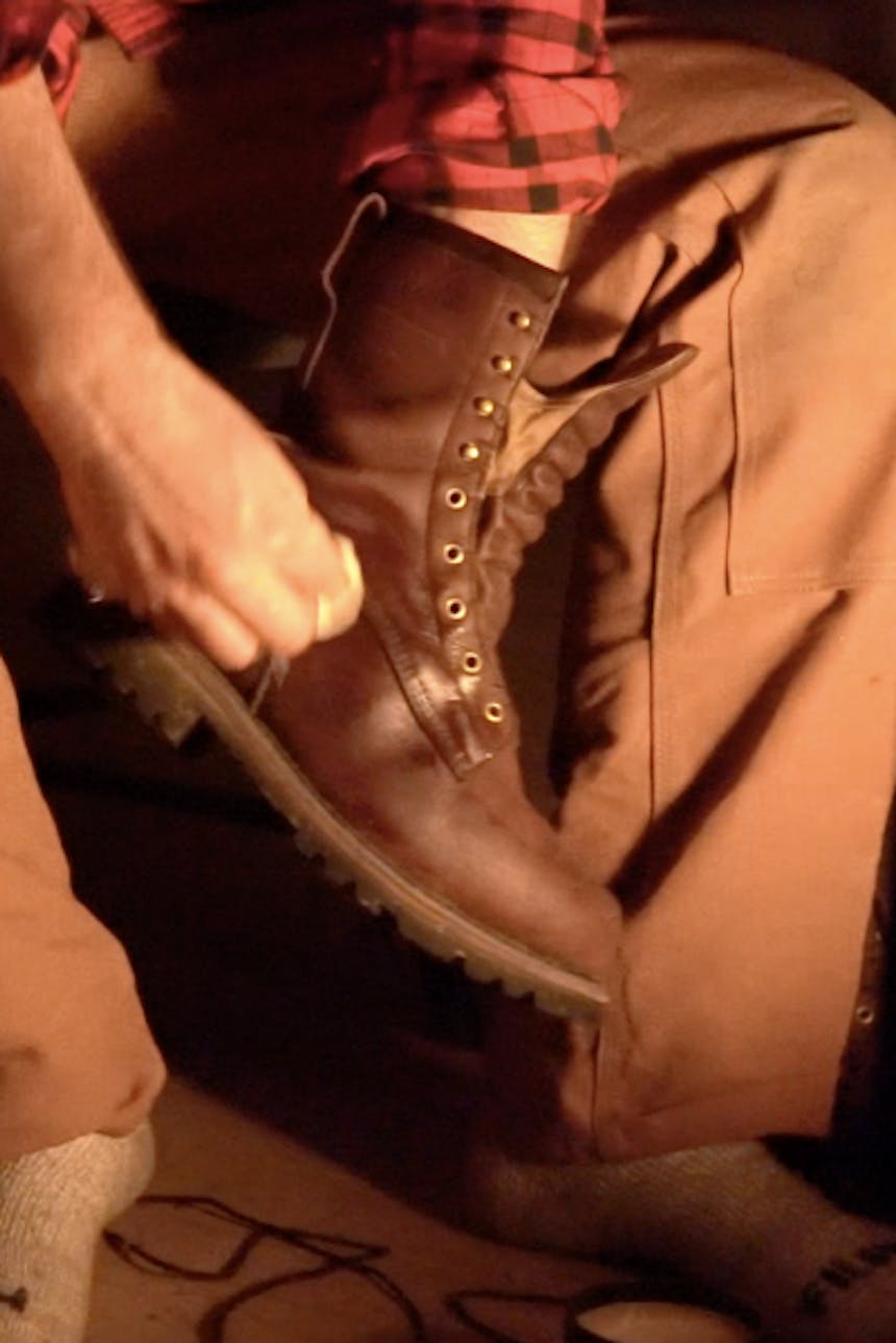 hand administering polish to unlaced brown boot with cloth