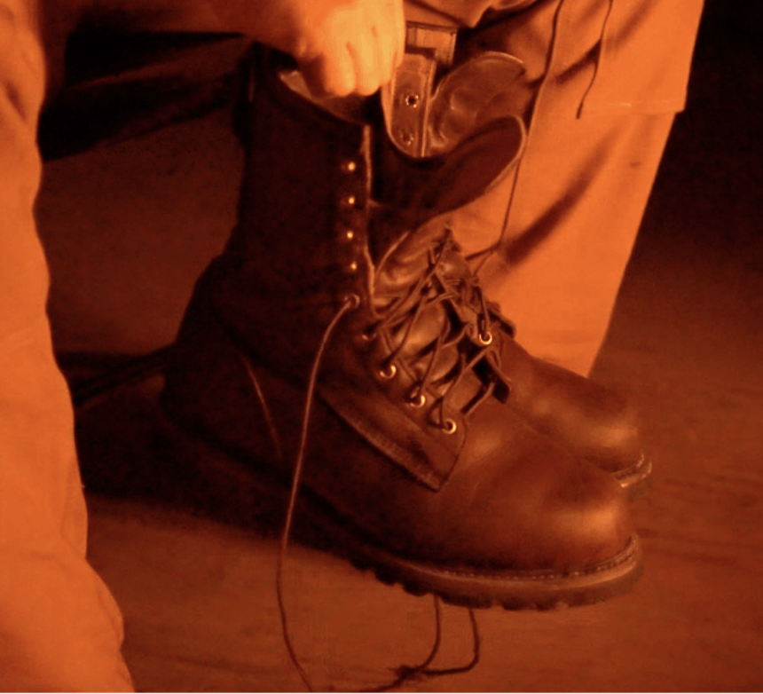 hand holding two pairs of brown boots