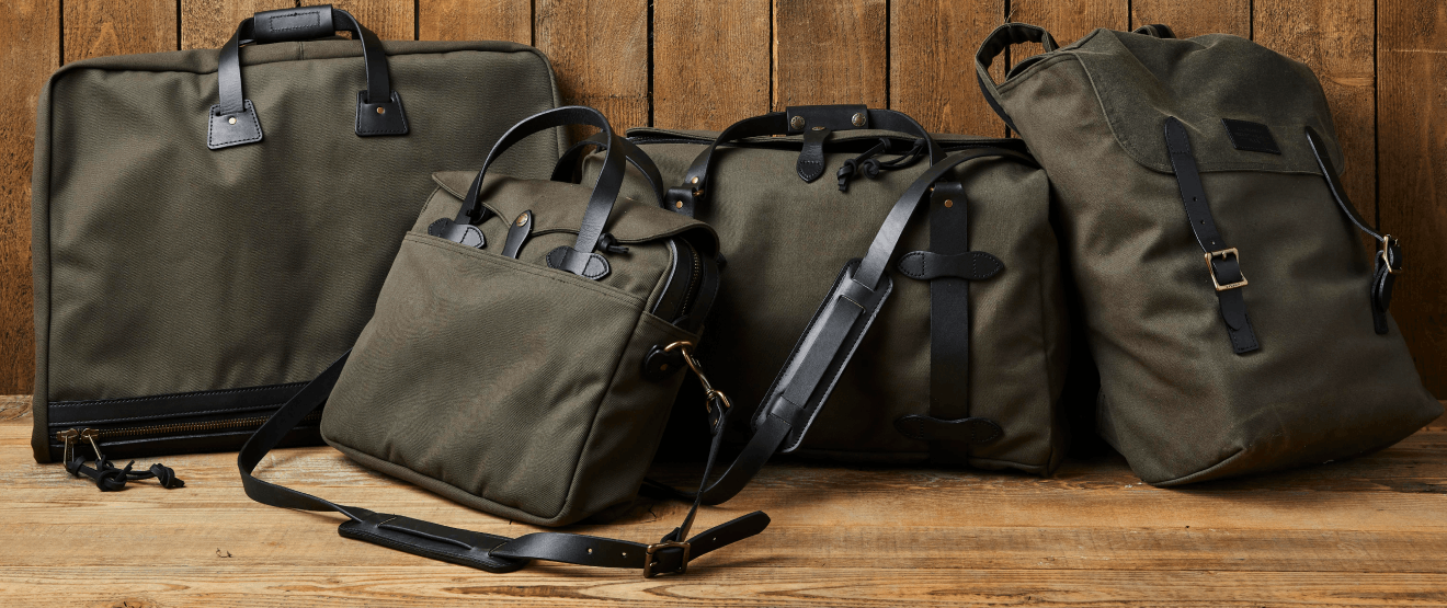 green filson bags lying next to a wooden wall