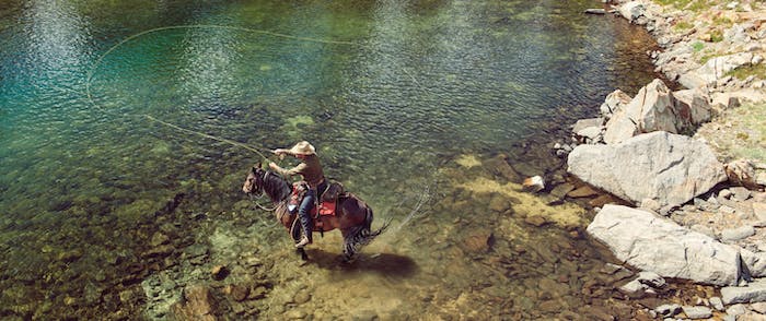 Man fly fishing from a horse in alpine lake